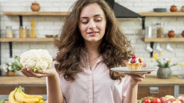 una giovane donna ha in mano un piatto con un dolce e un cavolo