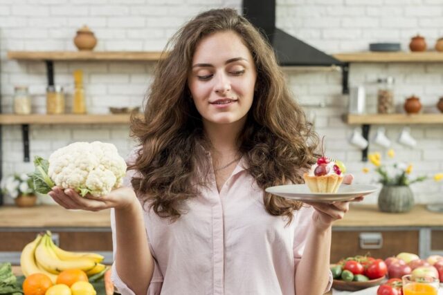 una giovane donna ha in mano un piatto con un dolce e un cavolo